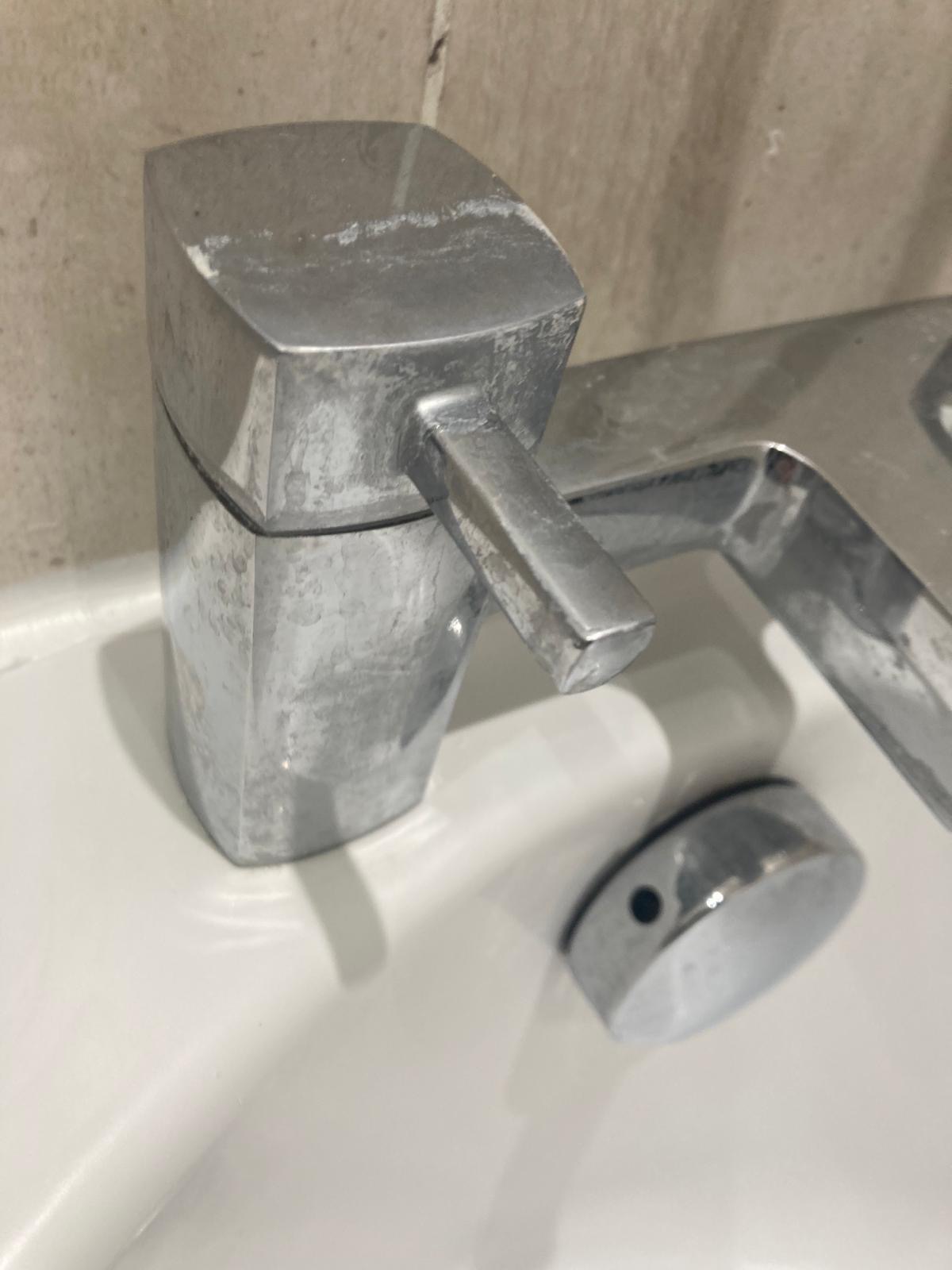 Polished bathroom sink and chrome taps after cleaning